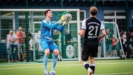 Torwart fängt den Ball vor einem Gegenspieler im Amateurfußball